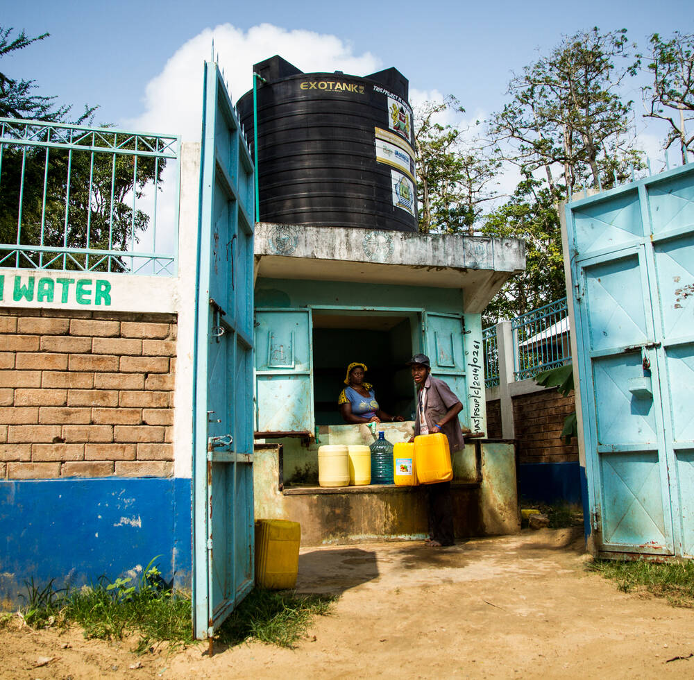 A resident buys water from the kiosk.