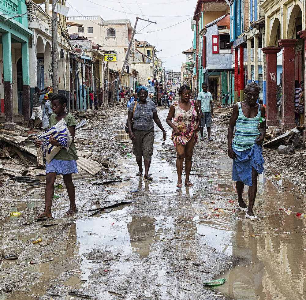People walk along a street in downtown Jeremie Haiti in 2016 after Hurricane Matthew